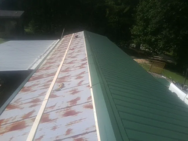 Old rusted panels beside newly installed green metal roofing — Wind Damage Roof Repair by Roofing Brothers in Palm City