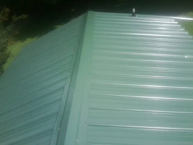 New green metal panels meeting at the ridge of a roof — Flat Roof Repair work by our crew in Palm City