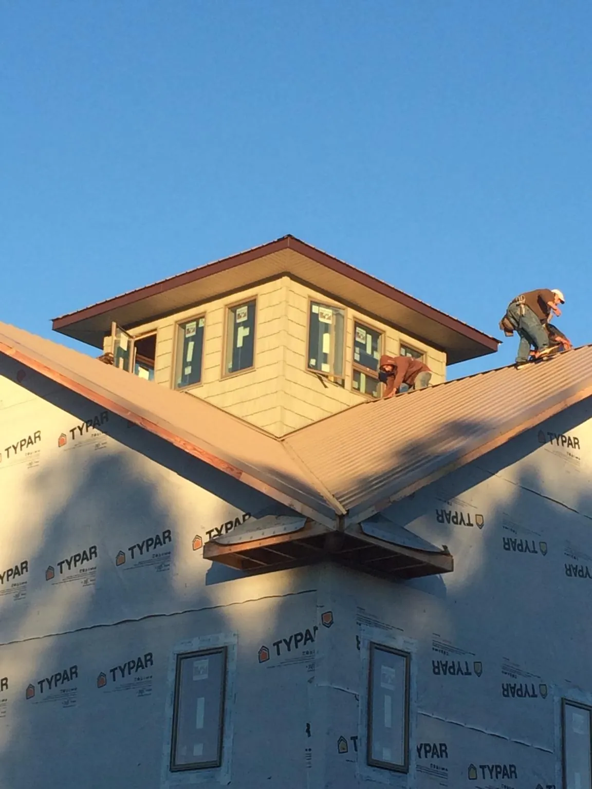Roofers working around a rooftop cupola on a new metal roof at sunset — Roof Waterproofing in Palm City by Roofing Brothers